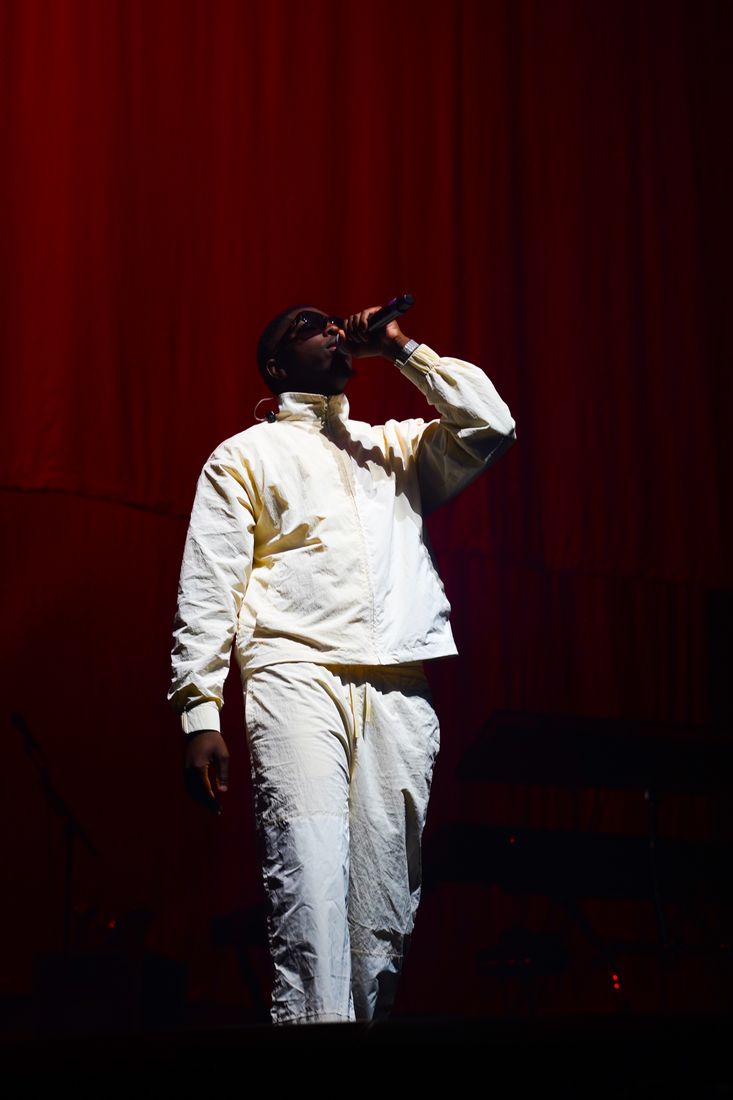 Rappeur en blanc devant un rideau rouge